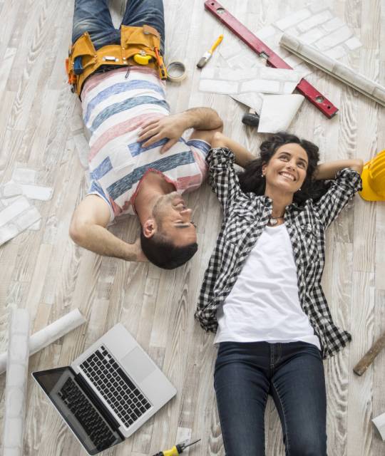 Couple renovating and resting on floor Couple renovating their home, resting and lying down on floor, high angle view.
